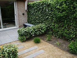 Terras van natuursteen dat doorloopt in de halfverharding.