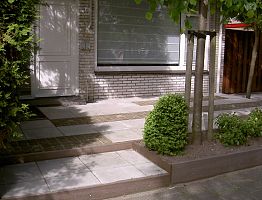 Voortuin met niveauverschil. Tegels afgewisseld met keitjes.