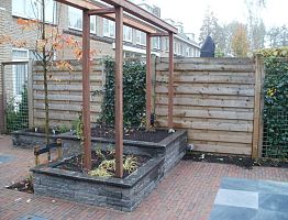 Verhoogde plantenbak aan de voet van een pergola.