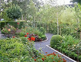 Strakke lijnen van het pad, gecombineerd met weelderige beplanting.