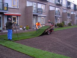 Aanleg grasveld: de zoden worden machinaal aangebracht.