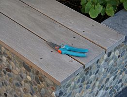 Detail van een bank op een met kiezels beklede plantenbak.